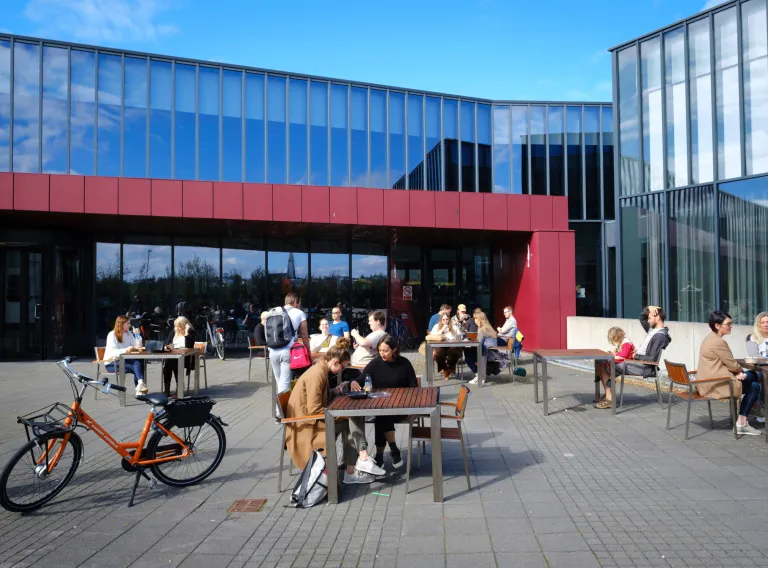 Fólk situr við borð úti hjá Háskólatorgi