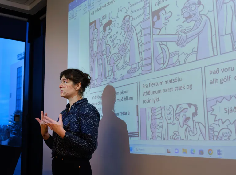 Einstaklingur flytur kynningu fyrir framan glærur í kennslustofu.