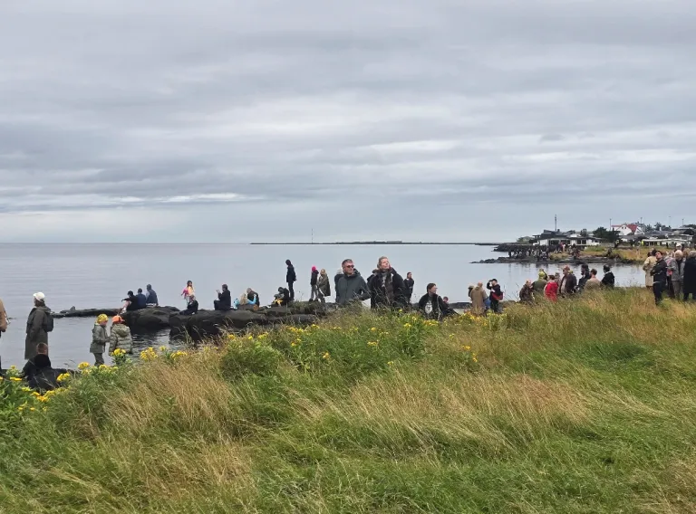fjöldi fólks og barna úti við sjó 