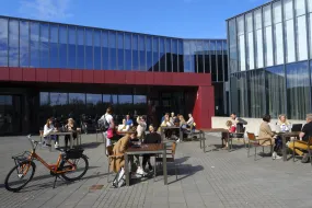Fólk situr fyrir utan Háskólatorg á björtum og sólríkum degi